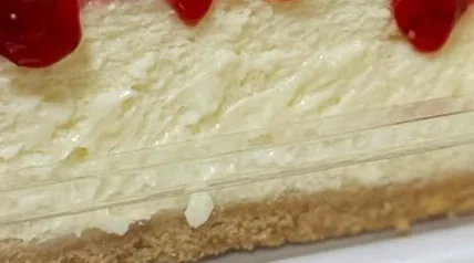 Fatia cremosa com base de biscoito e calda de frutas vermelhas