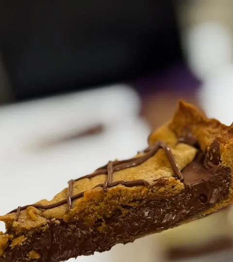 Fatia de torta cookie com recheio de Nutella e fios de chocolate por cima